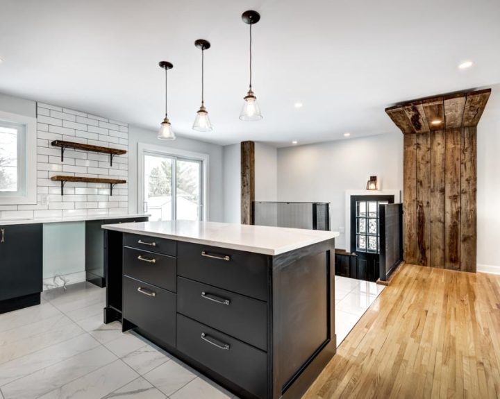 Modern farmhouse kitchen with black island, pendant lights, and subway tile backsplash by ParrotWerks Construction