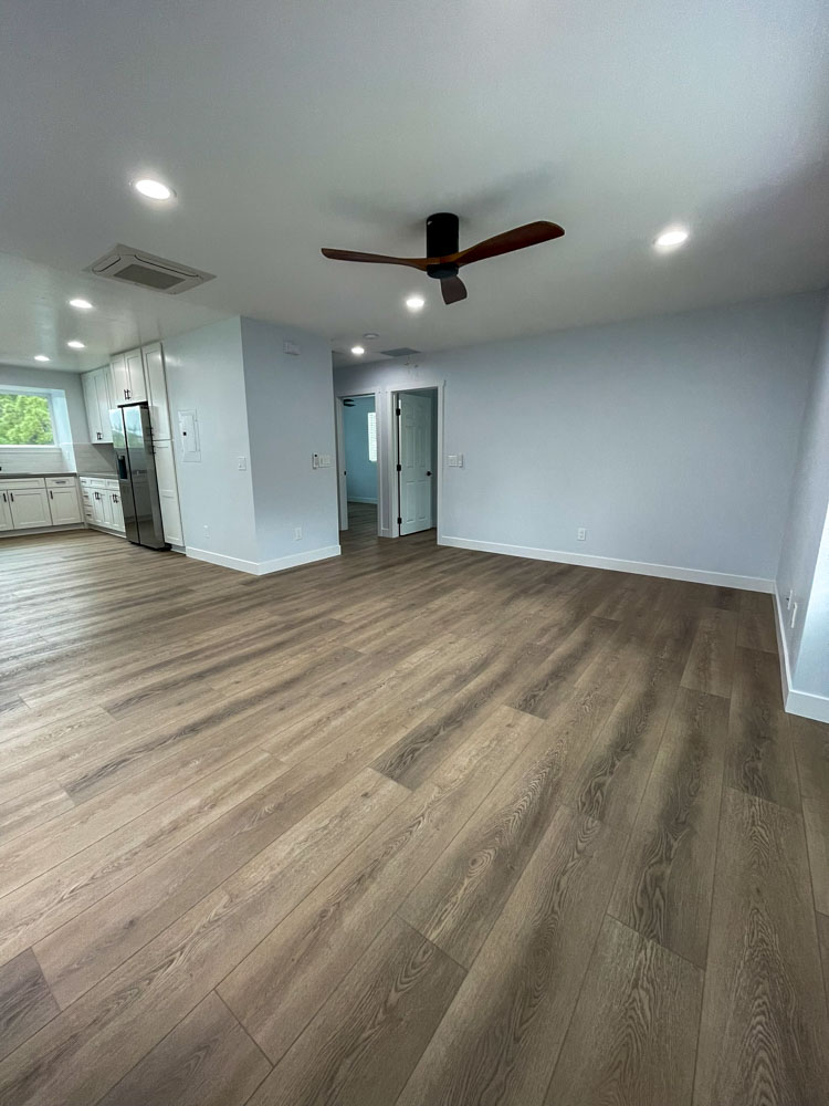 Renovated open-concept living space with hardwood floors and recessed lighting by ParrotWerks Construction