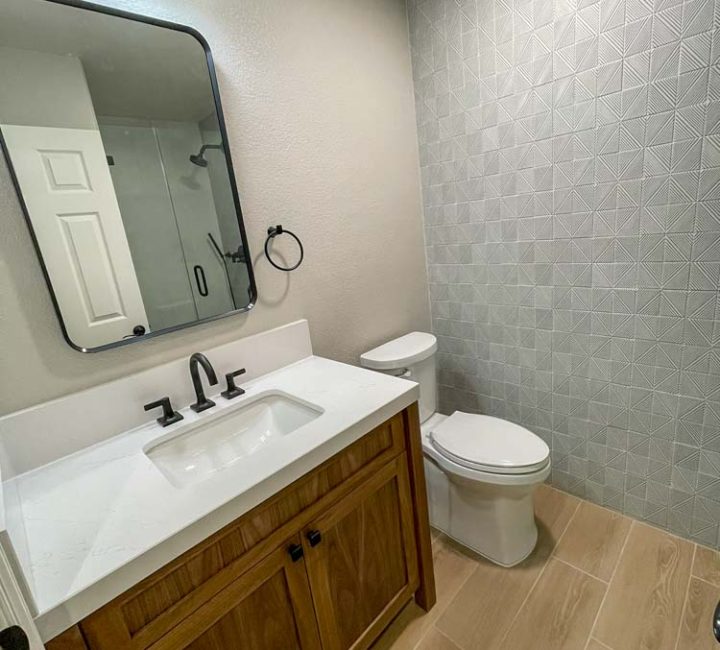 Modern bathroom remodel with wood vanity and textured accent wall by ParrotWerks Construction